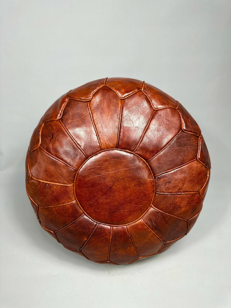 Brown leather ottoman on a light gray background