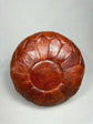 Brown leather ottoman on a light gray background